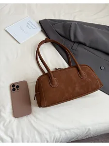 Brown suede baguette shoulder bag detail flat lay, featuring contrast white stitching design.