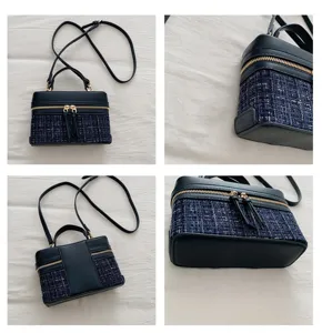 Detail view of navy blue tweed patchwork box handbag with gold zipper and handle.