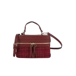 Close-up view of the burgundy tweed vanity bag showing metallic zippers, handle and leather trim.