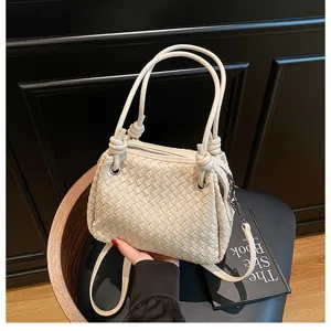 Detailed view of white woven leather shoulder handbag with metal knot and double top handles.