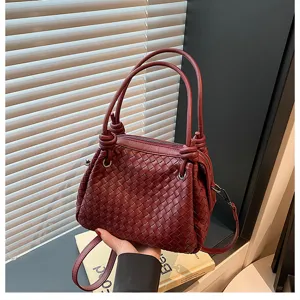 Detailed view of the dark red woven leather handbag featuring metal knot accents and handles.