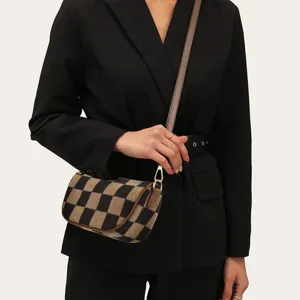 Detailed view of the stylish checkered canvas crossbody bag with contrast leather trim and strap.