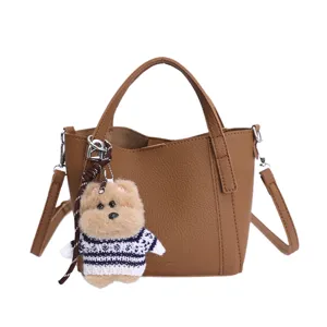 Brown PU leather bucket bag detail featuring cute fluffy bear keychain and top handle.