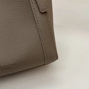 Detailed view of the taupe PU leather handbag showing fine litchi texture and neat stitching.