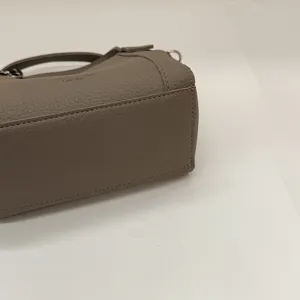Detailed view of grey pebbled PU leather handbag texture, side angle and fine stitching.