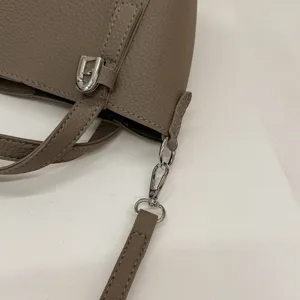 Close-up detail of taupe PU leather bucket bag hardware and strap connection, stylish style.