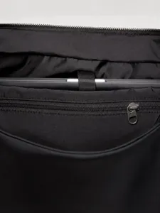 Black nylon crossbody bag interior detail showing laptop compartment and zipper pocket