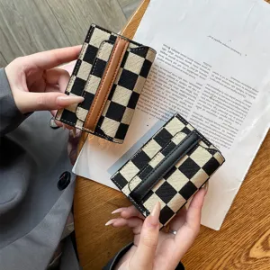 Detail shot of black and white checkered card holder with leather strap, multi-slot.