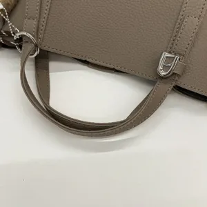 Close-up detail of the stylish litchi pattern PU leather handbag handle and silver hardware.