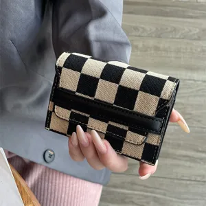 Detail shot of a chic black and beige checkerboard card holder wallet with flap and secure slots.