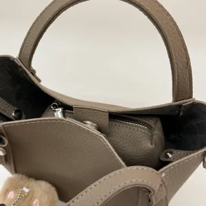 Detailed view of luxury textured PU leather bucket bag handle and inner zipper pouch.