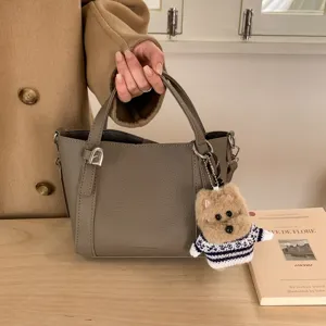 Grey PU leather bucket bag with cute bear charm, elegant crossbody handbag for women.