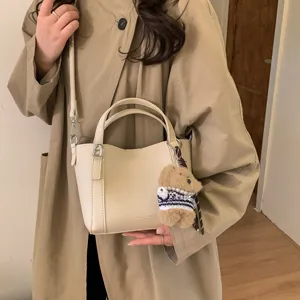 Retro litchi grain PU bucket bag for women, stylish crossbody handbag with cute bear pendant.