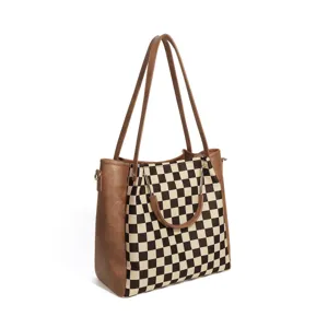 Black and white checkerboard tote bag detail showing brown leather trim and dual straps.