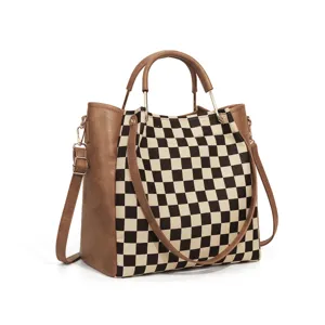 Close-up detail of the black and white checkerboard canvas and brown leather trim on the stylish bag.