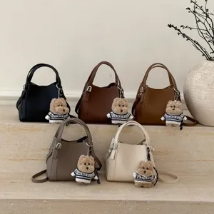 Retro PU leather bucket bag with cute bear pendant, trendy cross-body handbag for women.