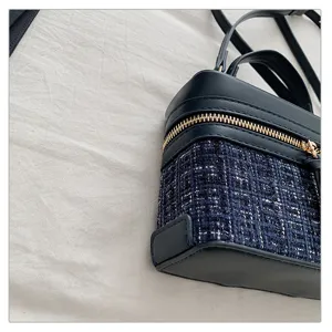 Close-up detail of luxury tweed vanity bag, navy blue fabric texture, gold zipper hardware.