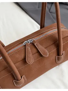 Retro brown leather baguette shoulder bag with chic white stitching and dual metal zippers.
