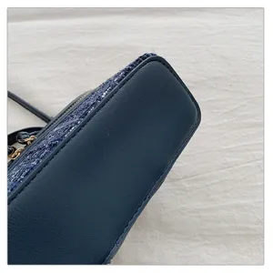 Detail shot of the dark blue leather and tweed handbag bottom, showing fine stitching and texture.