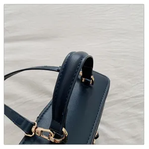 Detailed view of dark blue leather handbag handle and gold metal hardware, fine stitching.