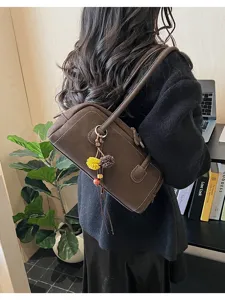 Close-up view of a stylish brown baguette shoulder bag with cute charms, elegant and chic.