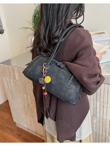 Detail view of a stylish retro baguette shoulder bag with chic charms in a natural lifestyle setting.
