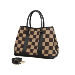 Detailed view of brown checkerboard canvas tote bag with black handles and strap hardware.
