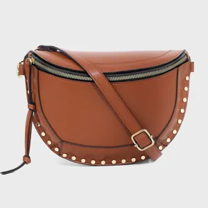 Detail view of brown leather crescent crossbody bag with gold tone studs and adjustable strap.