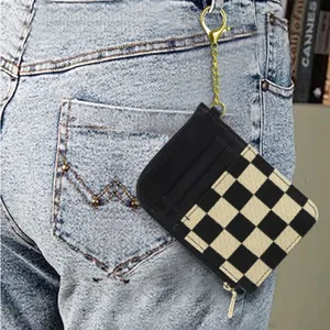 Detailed view of black and beige checkered card holder wallet featuring a golden chain keychain.