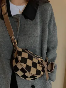 Detail shot of checkerboard canvas crossbody chest bag with small earphone pouch worn by model.