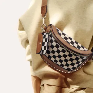 Close-up detail of trendy canvas checkerboard crossbody chest bag with chic metal studs and pouch.