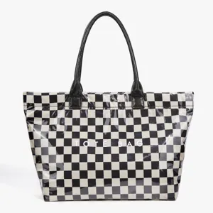Close-up detail of black and white checkered tote bag with patent leather handles.