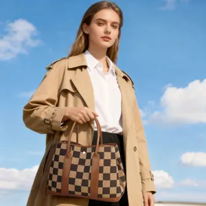 Detail shot of a checkerboard canvas tote handbag with brown leather trim in outdoor setting.