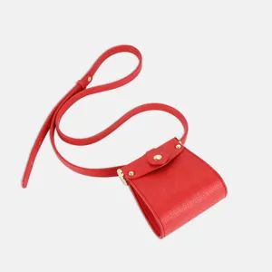 Close-up detail of the red PU leather mini crossbody pouch, showing fine strap and metal snap.