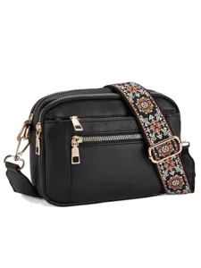 Close-up detail of black leather crossbody bag featuring ethnic embroidered wide strap.