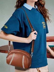 Brown leather baseball shaped crossbody shoulder bag with unique white stitching and zipper strap.