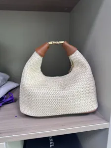 Woven straw hobo shoulder bag with brown leather handle and metal clasp for casual daily use.