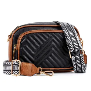 Detailed view of black and brown quilted crossbody bag with wide patterned strap and hardware.