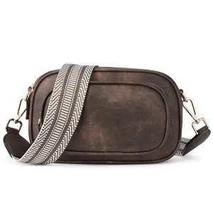 Detailed view of retro brown crossbody bag featuring wide woven strap and hardware.