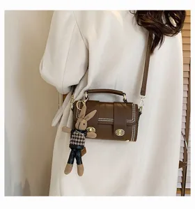 Gedetailleerd shot van de bruine retro crossbody tas met metalen slot en schattige konijnenhanger.