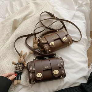 Retro bruine lederen crossbody tas met metalen draaisluiting en schattige konijnenhanger.
