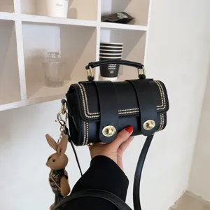 Zwarte elegante schoudertas met retro draaisluiting en schattige pluche konijnenhanger.