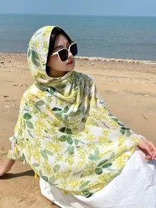 Detailed view of women green floral cotton linen beach shawl, summer sun protection scarf with tassels.