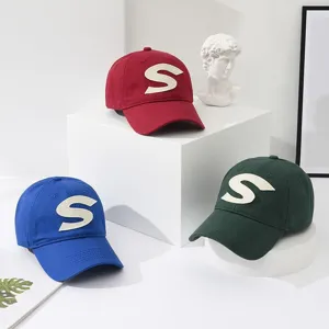 Detailed view of cotton baseball caps with embroidered letter S design in multi colors.