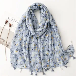 Floral print tassel scarf detail showing soft cotton linen texture and delicate flower pattern.