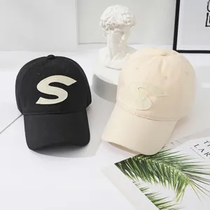 Detailed view of cotton baseball caps featuring embroidered letter S in a clean studio setting.