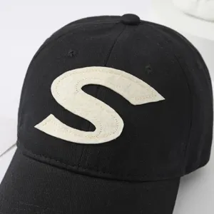 Black cotton baseball cap with bold white S letter embroidery detail, casual sports sun hat.