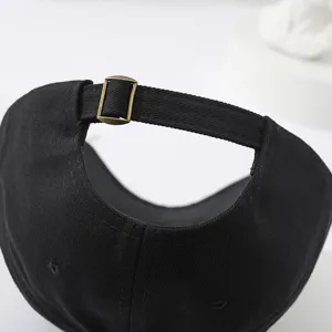 Close-up detail of the adjustable back strap and metal buckle on a black cotton baseball cap.