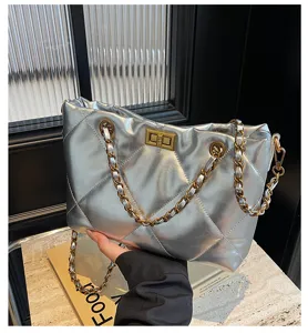 Detailaufnahme der eleganten silbernen gesteppten Tasche mit Metallketten und Drehverschluss.