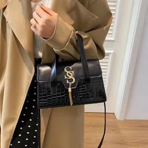 Elegante schwarze Handtasche mit Kroko-Muster, goldenem SS-Schloss und schickem Quasten-Anhänger.